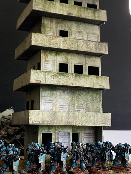 Warhammer 40k Apartment City Terrain with space marines. The tower is abandoned and delapidated.
